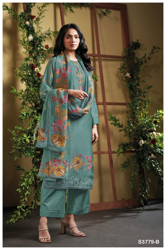 Woman wearing a teal embroidered outfit with a floral shawl in a decorated indoor setting.