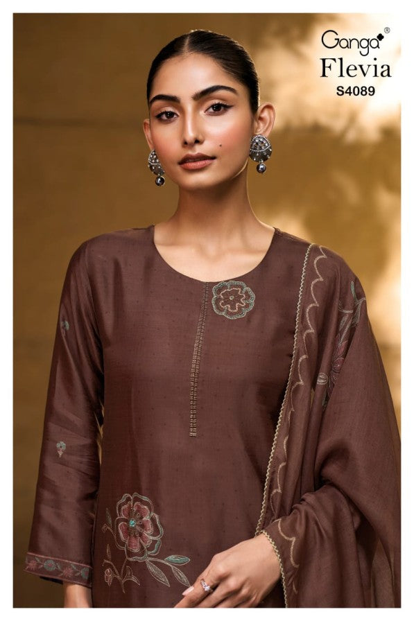 Woman wearing a brown embroidered outfit with a Ganga Flevia label in the corner.