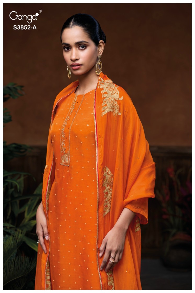 Woman wearing an orange traditional outfit with gold embroidery against a dark background